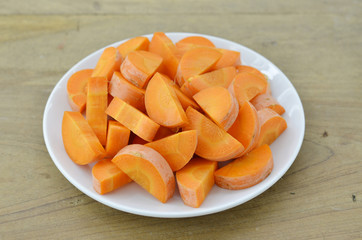White plate with cut carrots thin on wooden background