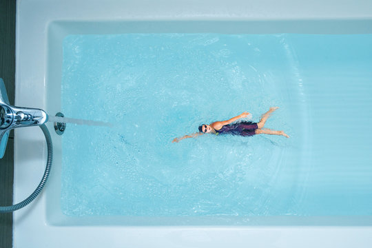 Stay Home And Stay Sporty. Woman Sports Swimmer Is Swimming In Bathroom Top View.