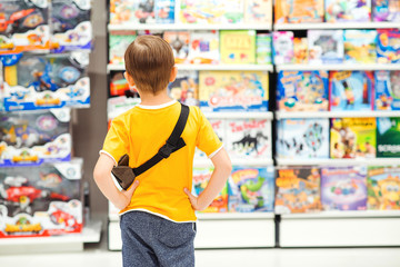 Little boy choosing toys for birthday gift. Many toys around. Kids shop. Sales, discounts and...