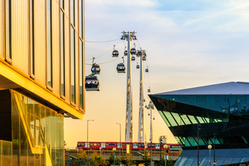 Royal Victoria Dock at sunset with Emirates air line cable car and docklands light railway  in...