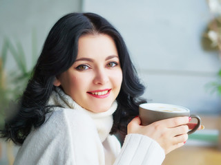 Coffee break. a Pretty Brunette girl in a white blouse, drinking coffee at a wooden table. copy space.