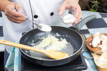 Chef putting flour in the pan prepared for cooking mushroom cream soup