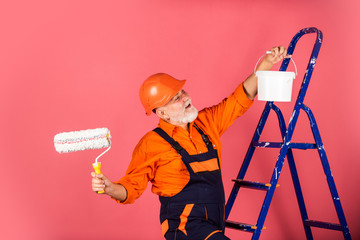 working in repair shop. senior man painter use roller on ladder. painting the wall in pink....
