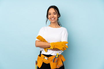 Young electrician woman isolated on blue background keeping the arms crossed in frontal position