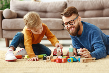 Happy dad and kid playing with toys at home.