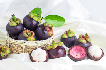 Mangosteen and cross section showing the thick purple skin and white flesh of the queen of friuts, Delicious mangosteen fruit arranged on a bowl, Mangosteen flesh, closeup. Mangosteen.