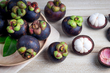Mangosteen and cross section showing the thick purple skin and white flesh of the queen of friuts, Delicious mangosteen fruit arranged on a bowl, Mangosteen flesh, closeup. Mangosteen.