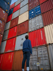 Man looking up at shipping containers in shipyard