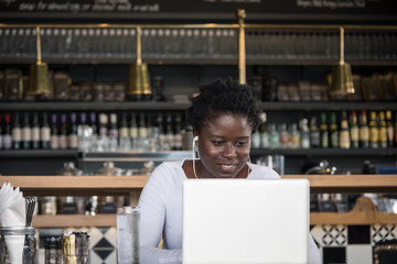 Young smiling African woman with laptop in coffee shop