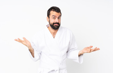 Young man doing karate over isolated white background making doubts gesture