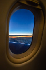 Sunset view over the clouds from the porthole of an airplane
