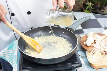 Chef pouring soup the pan for cooking mushroom cream soup