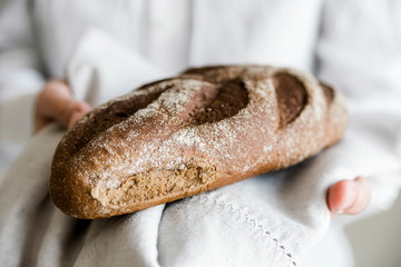 Whole wheat bread in hands.Homemade freshly baked bread.Brown tommy.Healthy food.Close-up view