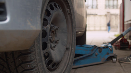 Fototapeta premium Mechanic in a vehicle workshop lifting a car on a jack