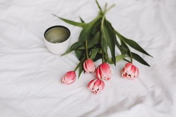 Coffee cup and tulips in bed. Concept of holiday, birthday, Women Day. Breakfast in bed. Good morning. still life, flat lay