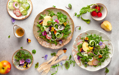 Delicious summer salad with edible flowers, vegetables, fruit, microgreens and cheese. Clean and...