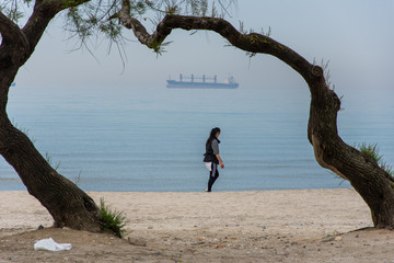 Istanbul/Turkey - 05.11.2020: A woman walking while making gymnastics near Marmara sea. Ship on the background