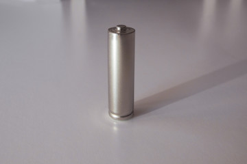 A gray AA model battery stands upright on a white background