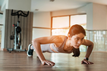 Beautiful young Asian woman doing push ups in the gym 