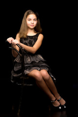 Portrait of a little girl sitting on an old Viennese chair, blac.