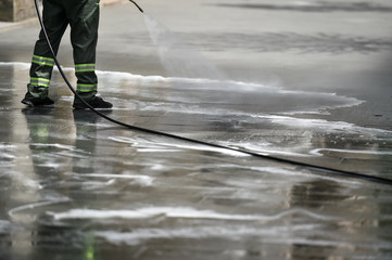 Public janitor deep cleaning the sidewalk and cycling lane with high pressure disinfectant solution...