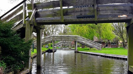 View of a canal with wooden bridges in the famous typical Dutch village Giethoorn, called the Venice of the Netherlands or Venice of the North.
