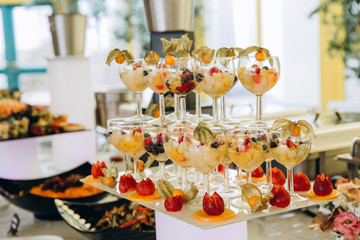 Glasses with berries and fruits. Fruit salad. Dessert on the festive table.