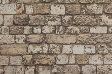 Old stable stone wall with rows of crafted masonry stones. Brickwork with individual craft bricks pattern. Strong manual work construction build has stability. Nice creativity vintage pattern