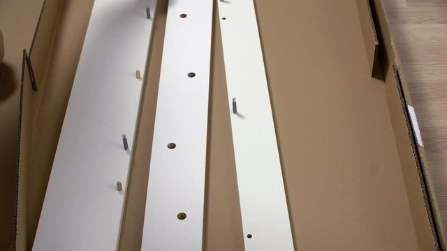 Close up view of repairman attaching wooden pegs in particle board. Cropped view of man assembling furniture at home. Home improvement concept