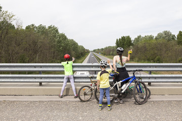 3 kinder winken den autos auf der autobahn zu während eines fahrradtour