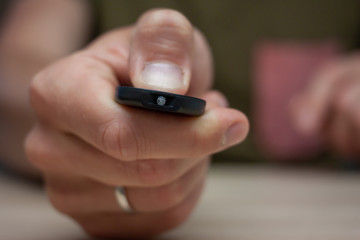male hand keeps remote control press the button