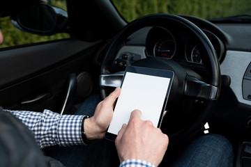 Man sitting in a car and using mobile device.