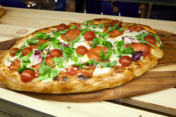 pizza with cherry tomatoes arugula leaves and mozzarella