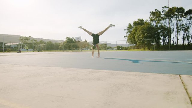 Young Woman Does Split Handstand Outside on Sunny Morning. Wide Shot