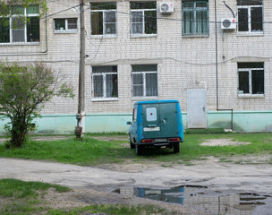 old blue soviet car on the background of a brick building