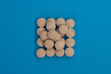 Light brown pills on a blue background.