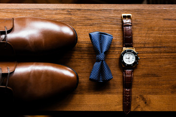 Men's accessories, perfume, boutonniere, gold rings, watches and leather shoes of the groom.