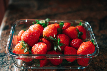 Glass container full of precious fresh strawberries in the home kitchen. Low calorie healthy food, like fruit.