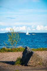 Blue sea from the shore on a sunny summer day with an island and a ship in the horizon.