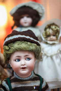 Tr&ecirc;s bonecos de porcelana muito antigos, com nitidez no primeiro boneco e os demais desfocados.