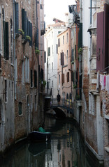 Fototapeta na wymiar Photo of canal in Venice with historical facades ,man on the bridge and boat in the evening.