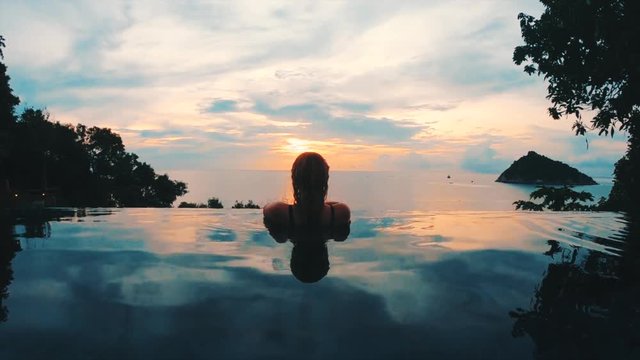 beautiful girl gazing out of luxurious infinity pool