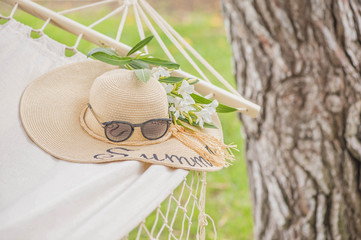 Straw hat on a hammock in a sunny summer day. Rest in the garden. Summer time fun