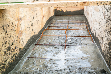 Steel rod reinforcement during pouring concrete into wooden frame