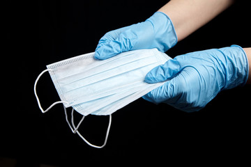 Person holding medical face masks, disposable sanitary surgical masks in hand in blue glove