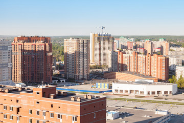Fototapeta premium A new family-friendly neighborhood with tall buildings made of brown brick and a large garage with multi-level parking, a building project that meets the requirements of the mortgage market.