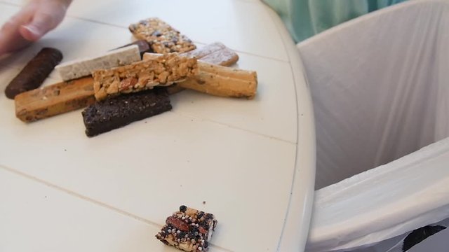 Throwing away nutrition protein bars into trash slow motion