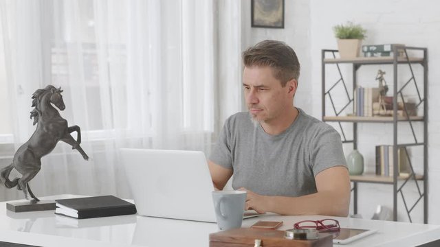 Man working from home online with laptop computer in home office.