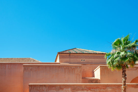 Typical Moroccan architecture, a traditional building with Islamic and Berber influences, showing peachy shade of soft terracotta walls and rooftops under the strong African sun in Marrakech, Morocco - Powered by Adobe