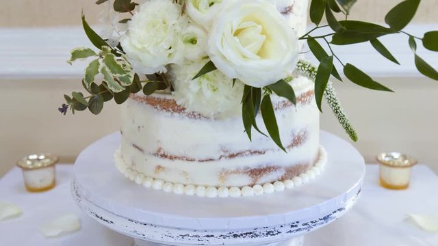 Close up of beautiful white wedding cake with white and green flower decorations